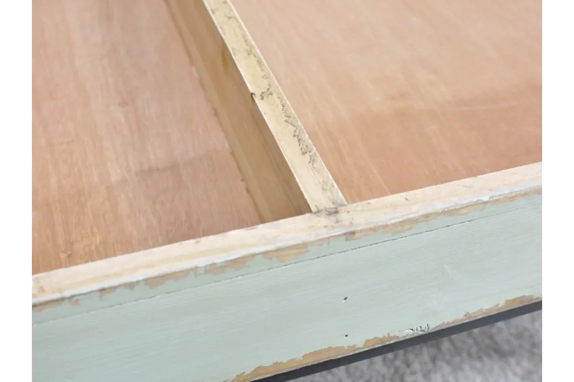 Close-up of distressed wooden drawer with light painted front and natural wood interior