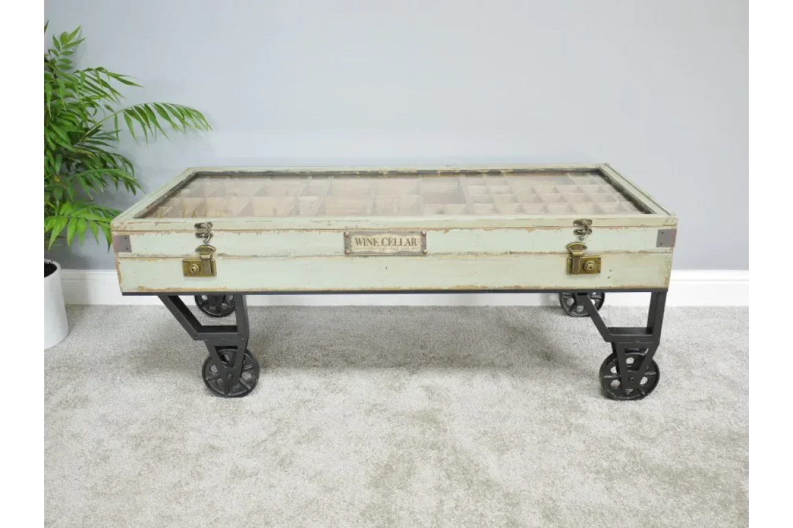 Vintage trunk coffee table with glass top, metal legs, caster wheels, and wine cellar label
