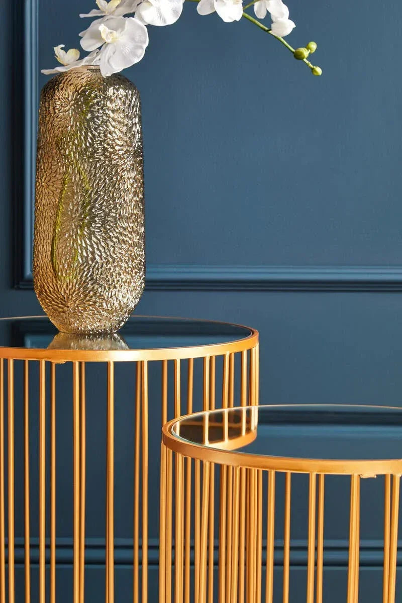 Gold metal side table set with glass tops, textured vase and white orchid flowers