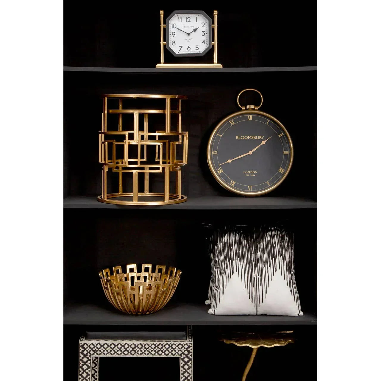 Gold accent decor including geometric bowl, black and gold wall clock, cushion on dark shelving
