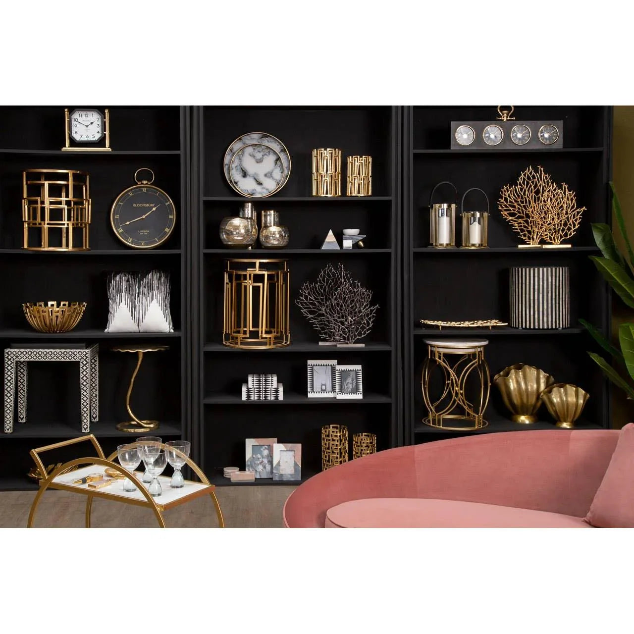 Black shelving unit with gold home decor, decorative bowls, clocks, and ornaments