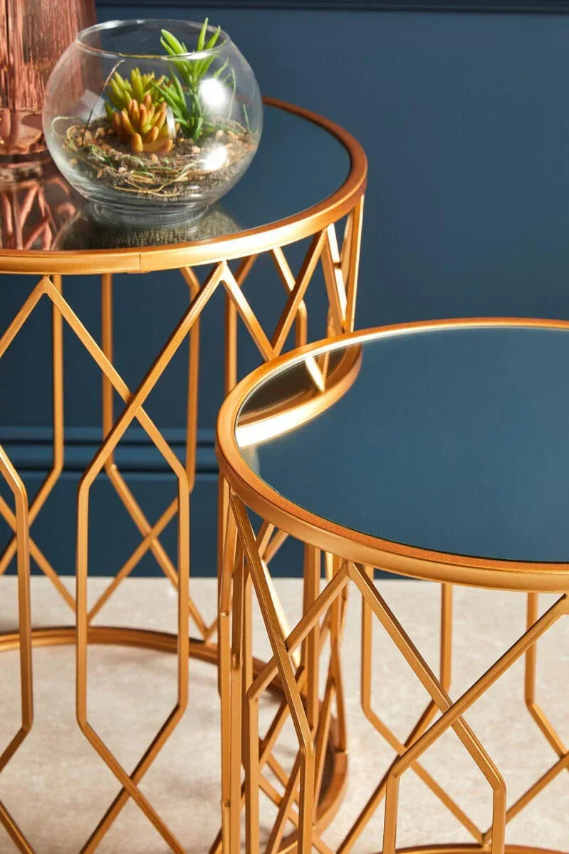 Gold geometric metal side tables with glass tops, one holding a round glass plant terrarium