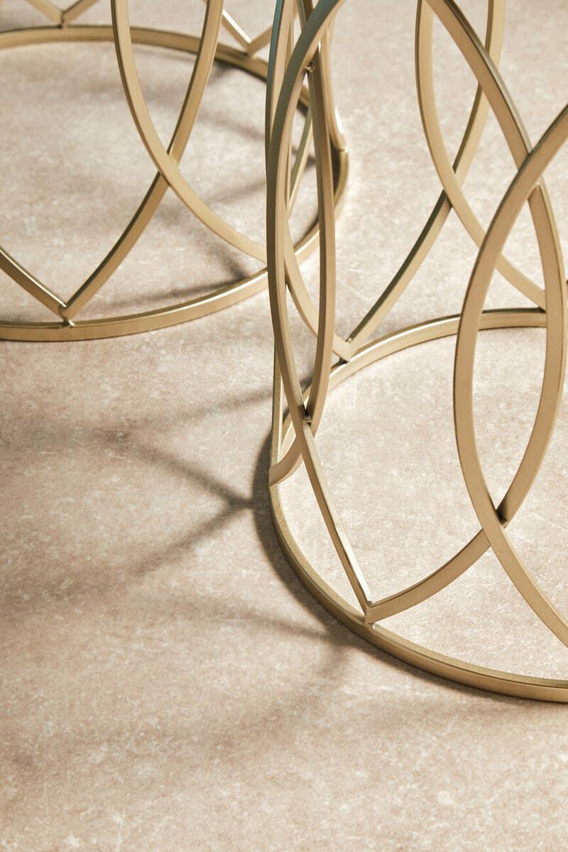 Gold metal coffee table base with geometric openwork design on stone floor