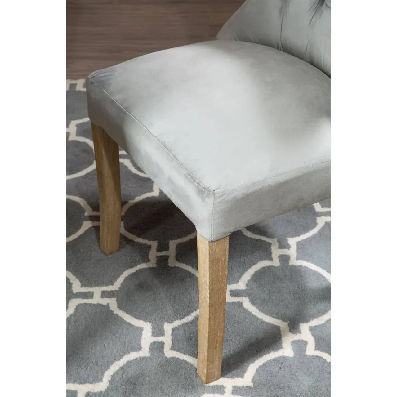 Light grey upholstered dining chair with wooden legs on grey patterned rug