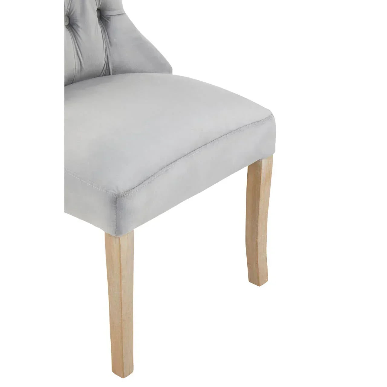 Light grey upholstered dining chair with tufted back and natural wood legs, side view