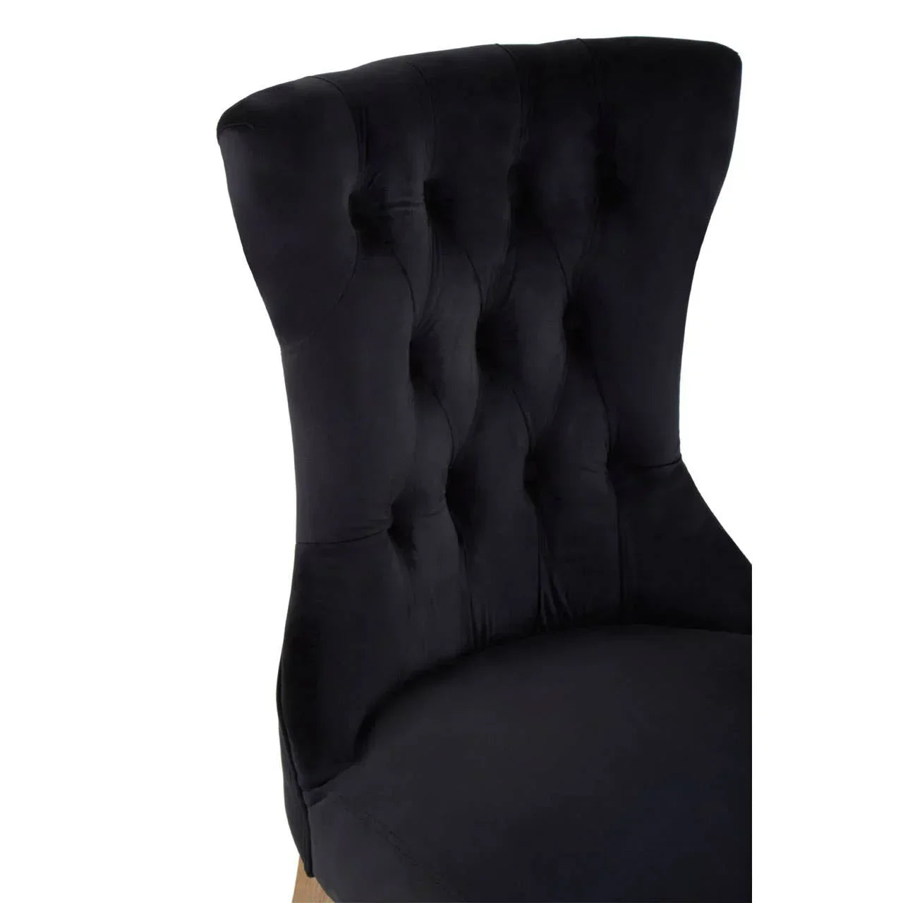 Black velvet dining chair with button tufted backrest and curved seat detail