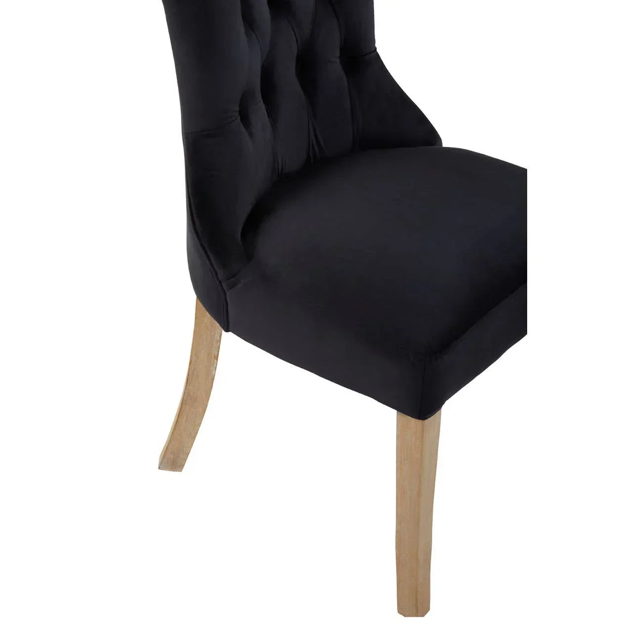 Black upholstered dining chair with buttoned back and light wooden legs, side angle view
