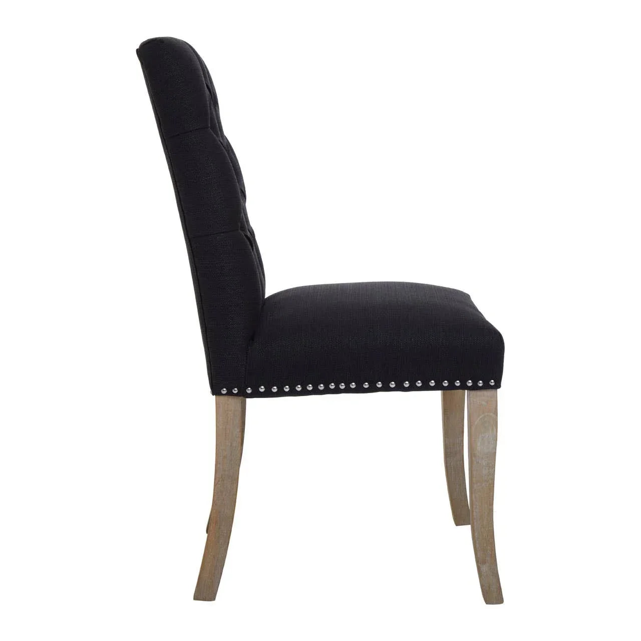 Black upholstered dining chair with button back and stud detail, side view on wooden legs