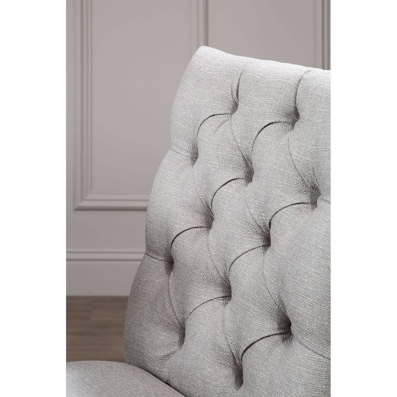 Light grey fabric dining chair with deep button tufted backrest, closeup angle