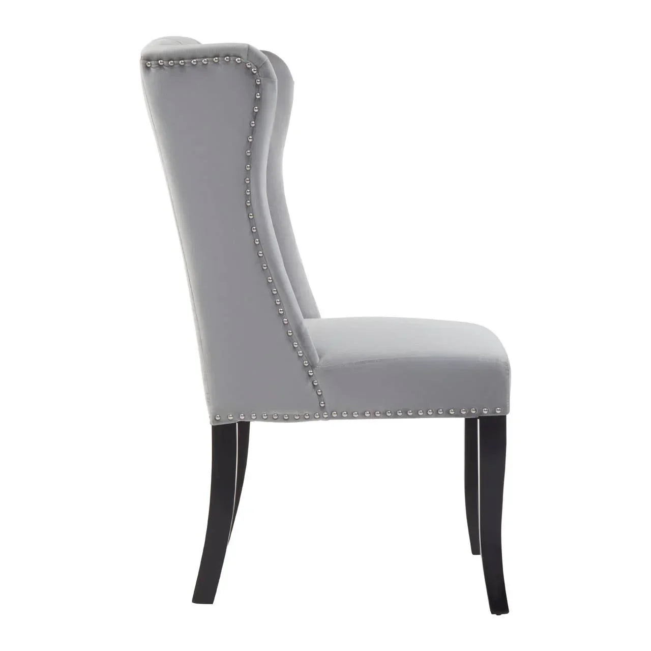 Grey velvet dining chair with silver stud detail and black wooden legs, side profile view