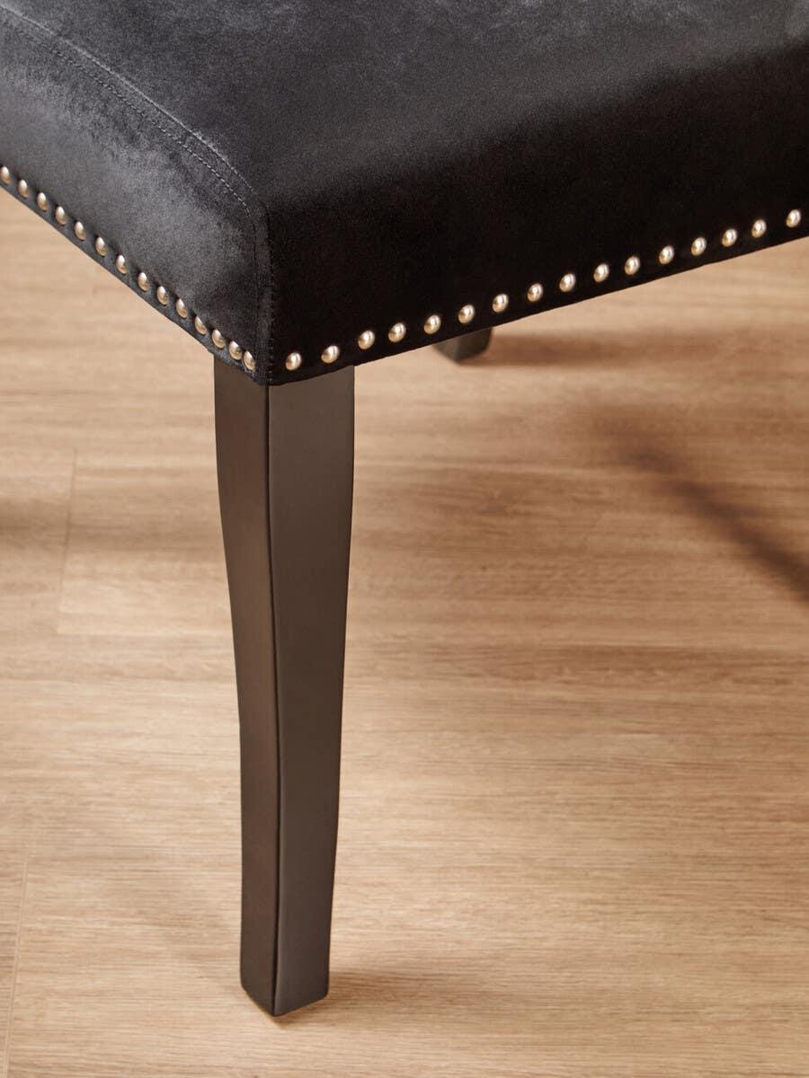 Black velvet dining chair with stud detail and dark wooden legs on wood floor