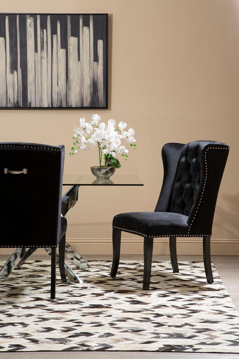 Black velvet dining chairs with silver studs and glass table on patterned rug