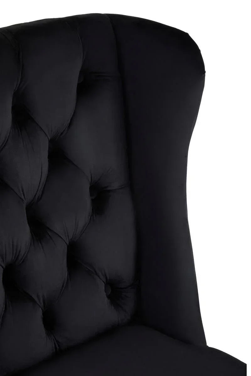 Black upholstered chair with deep button tufting and high backrest, close-up view