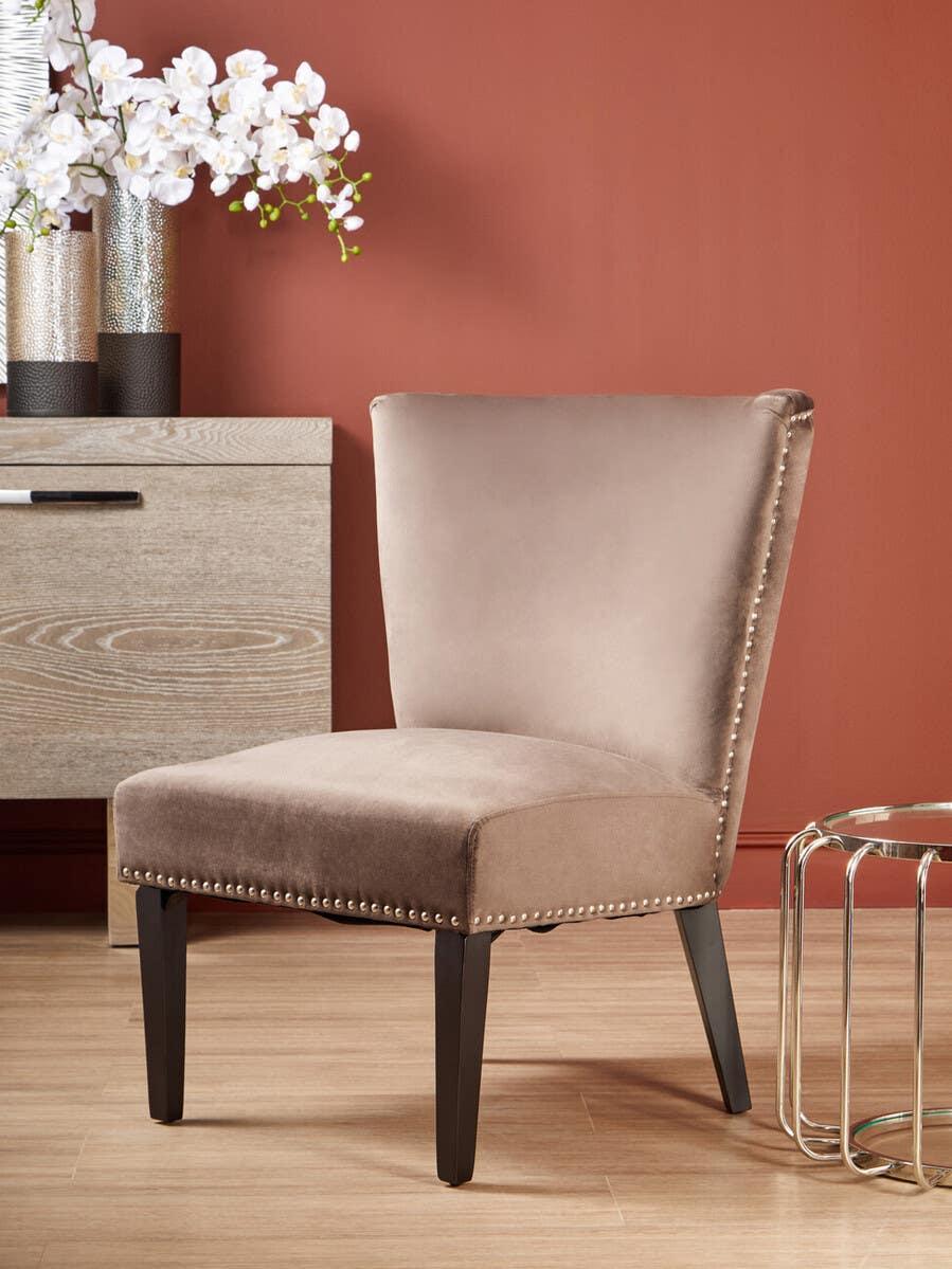 Taupe velvet accent chair with studded trim and dark wood legs in modern living space