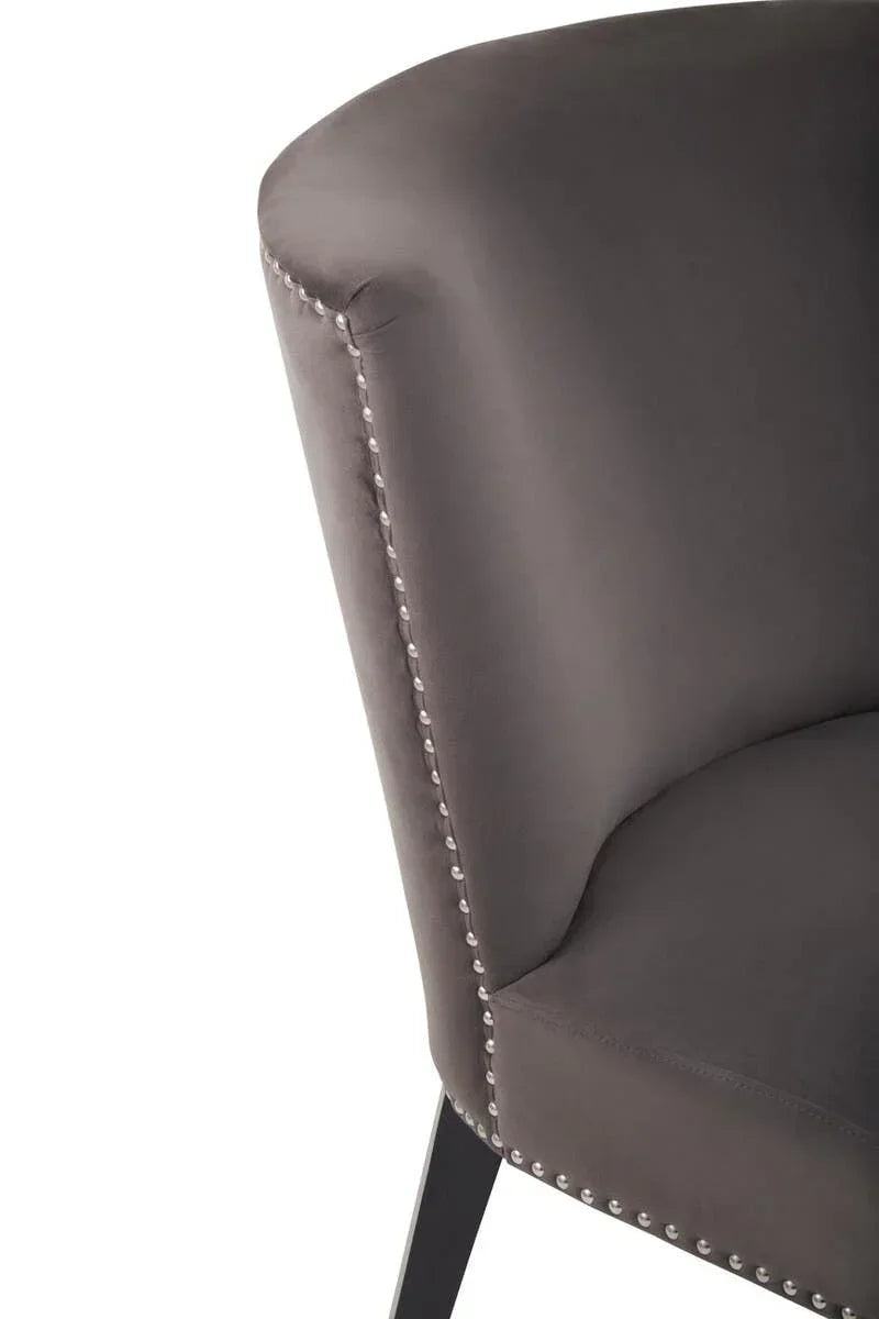 Grey upholstered accent chair with studded trim and black leg close-up