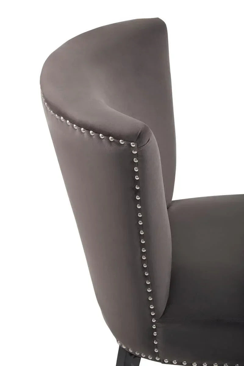 Grey velvet dining chair with studded trim and curved backrest closeup