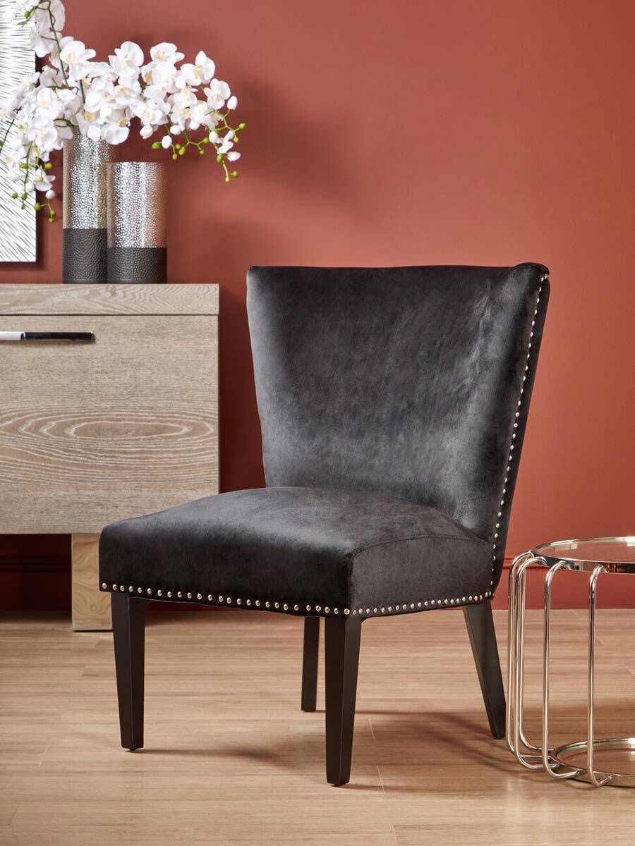 Dark grey upholstered accent chair with studded trim and black legs in modern living room