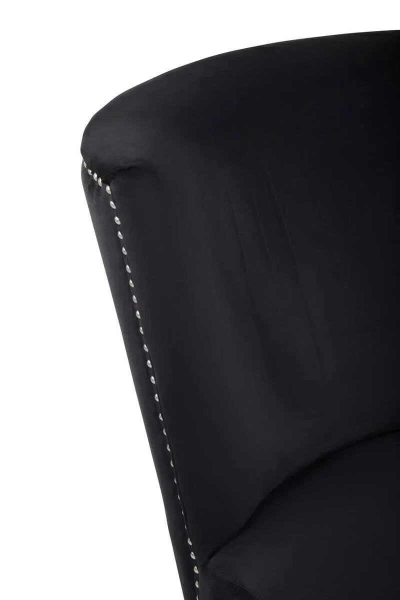 Black velvet armchair close-up showing curved backrest and silver stud detailing