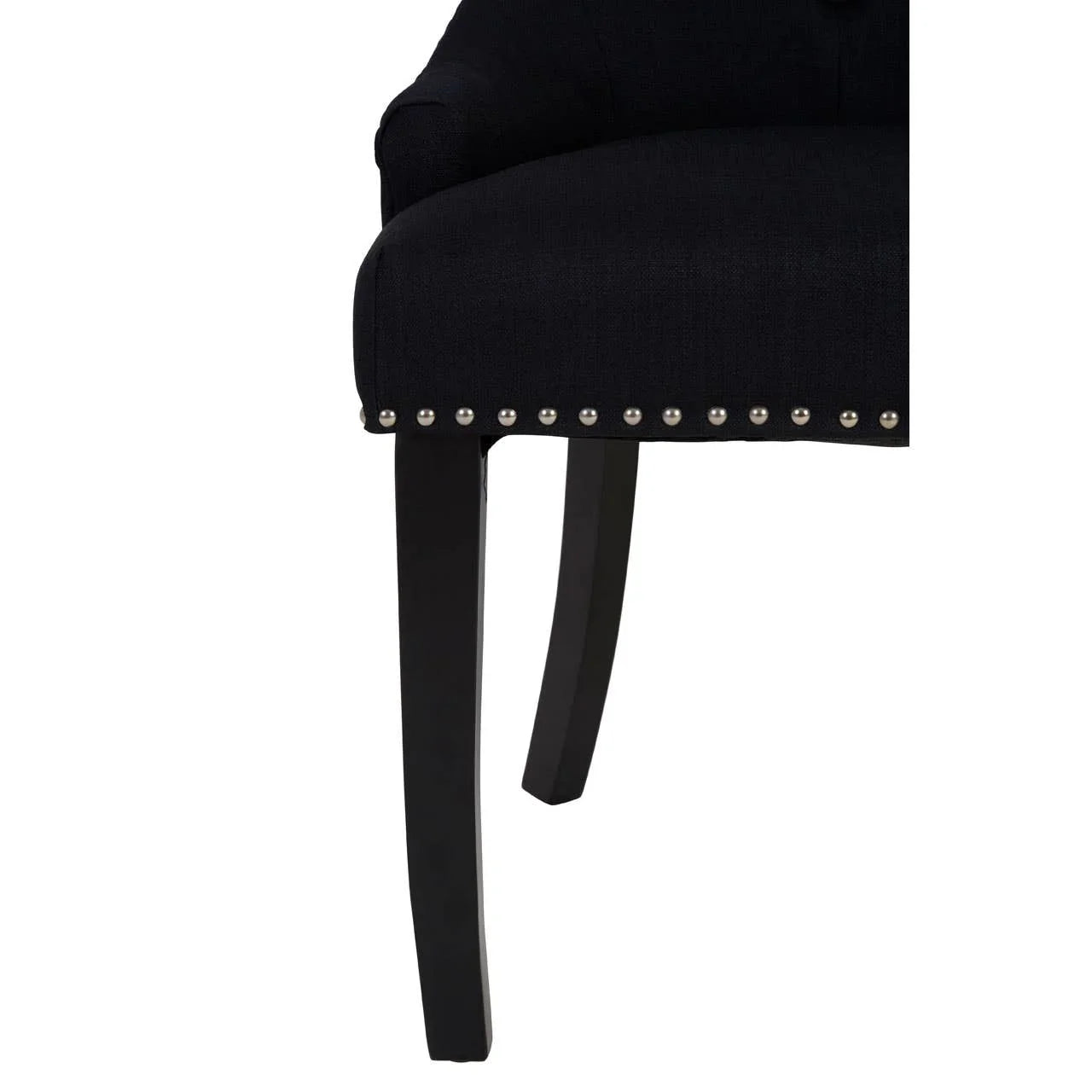 Black fabric dining chair close-up with dark wood legs and silver stud detailing