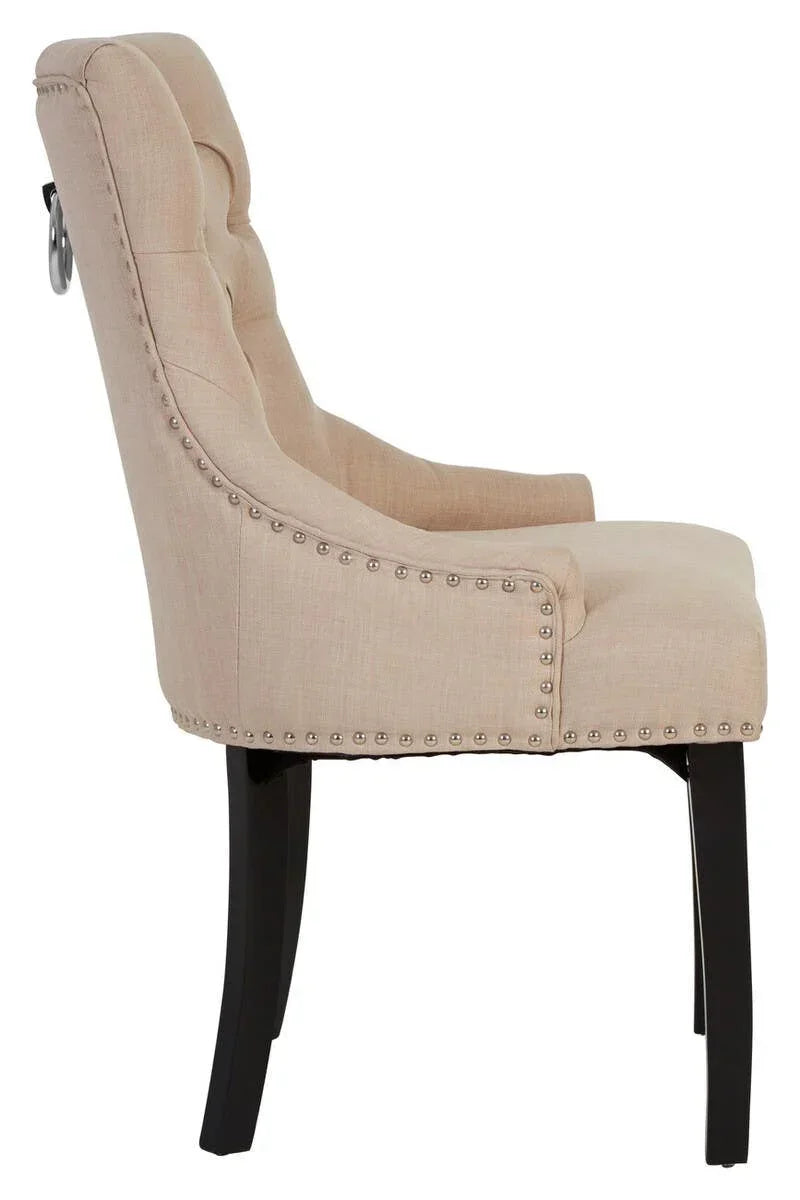 Beige upholstered dining chair with button tufting and nailhead trim, side profile view