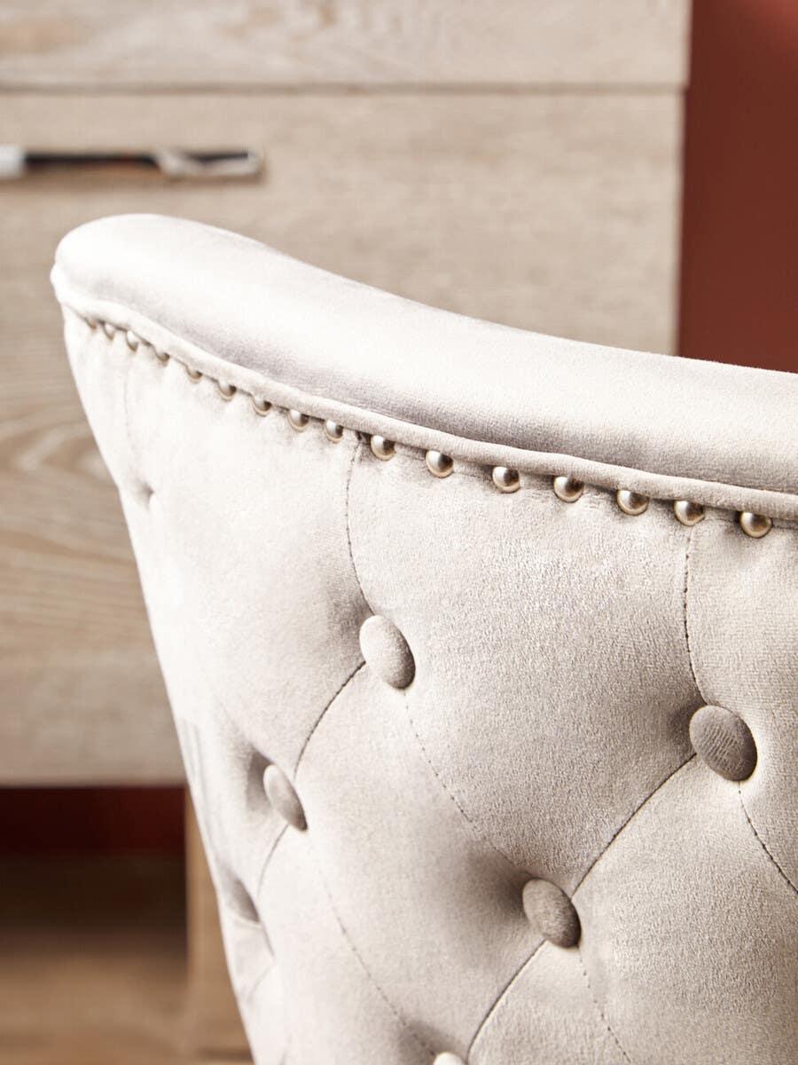 Close view of velvet dining chair with button tufting and studded trim