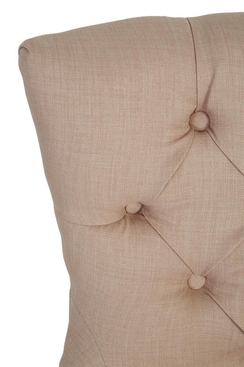 Close-up of beige fabric upholstered bed headboard with button tufting