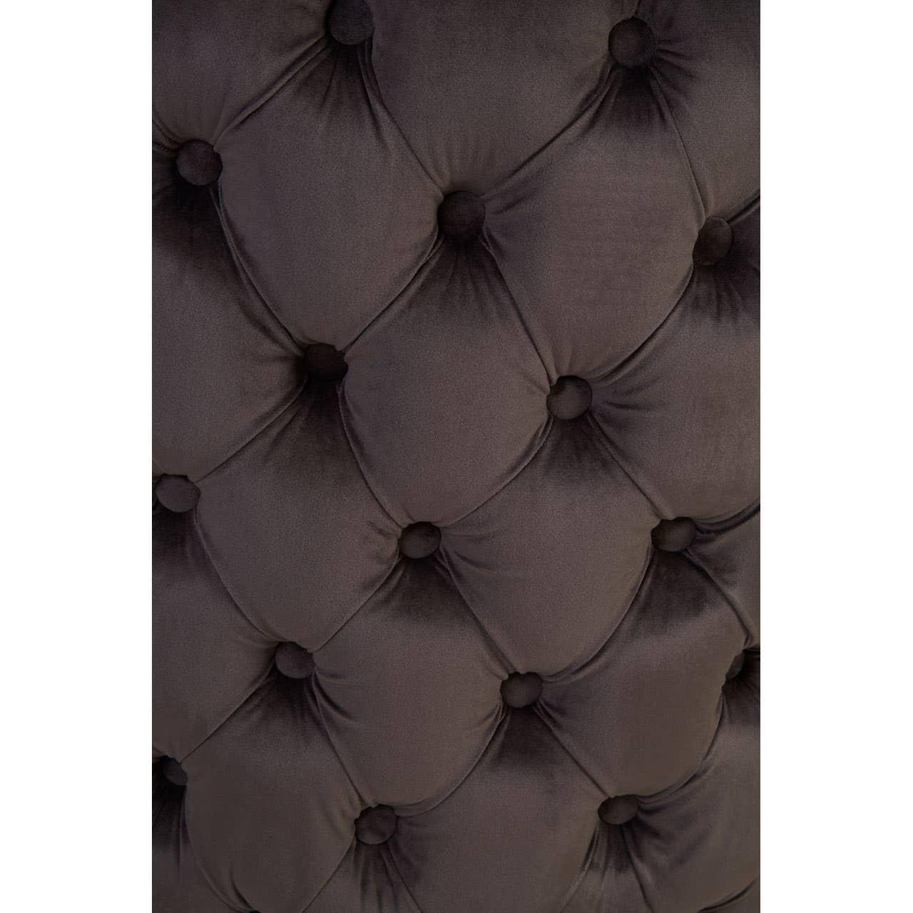 Close-up of dark velvet upholstered headboard with deep button tufting