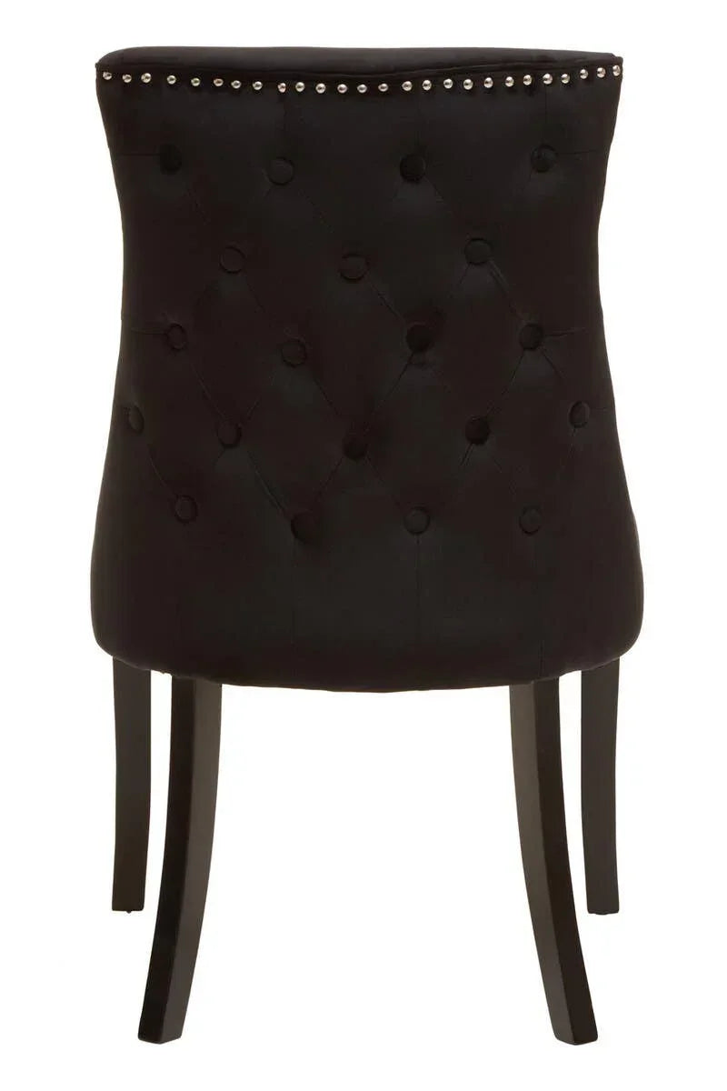 Black velvet dining chair with button-tufted backrest and silver nailhead trim, rear view
