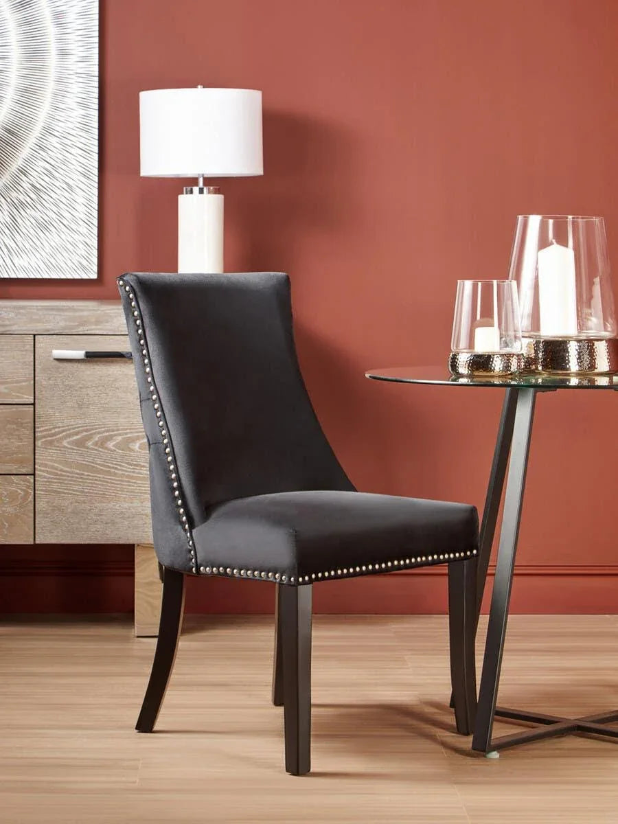 Velvet dining chair with silver stud detail beside glass table and wooden sideboard