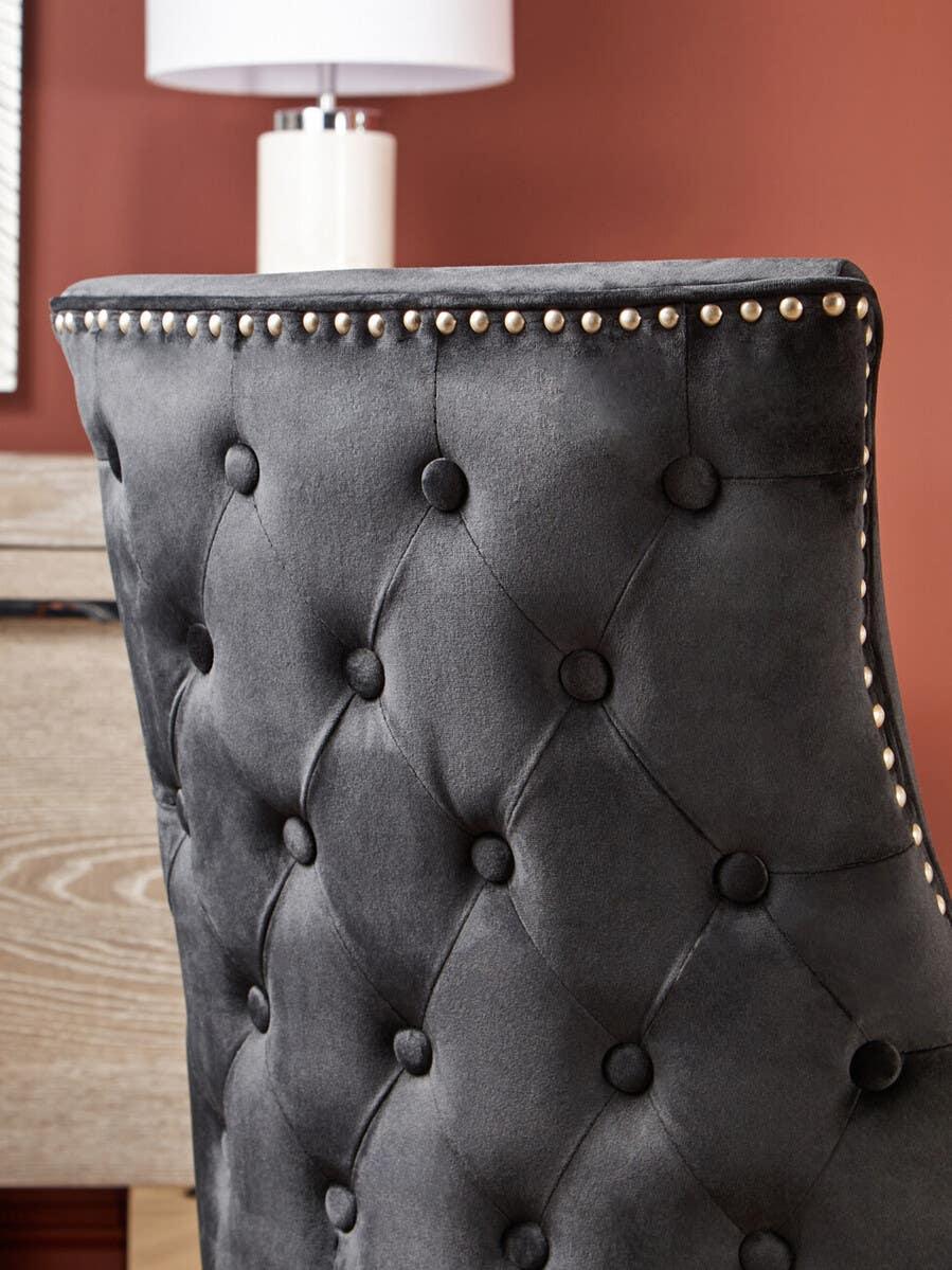 Grey velvet upholstered dining chair with button tufting and metal stud detailing