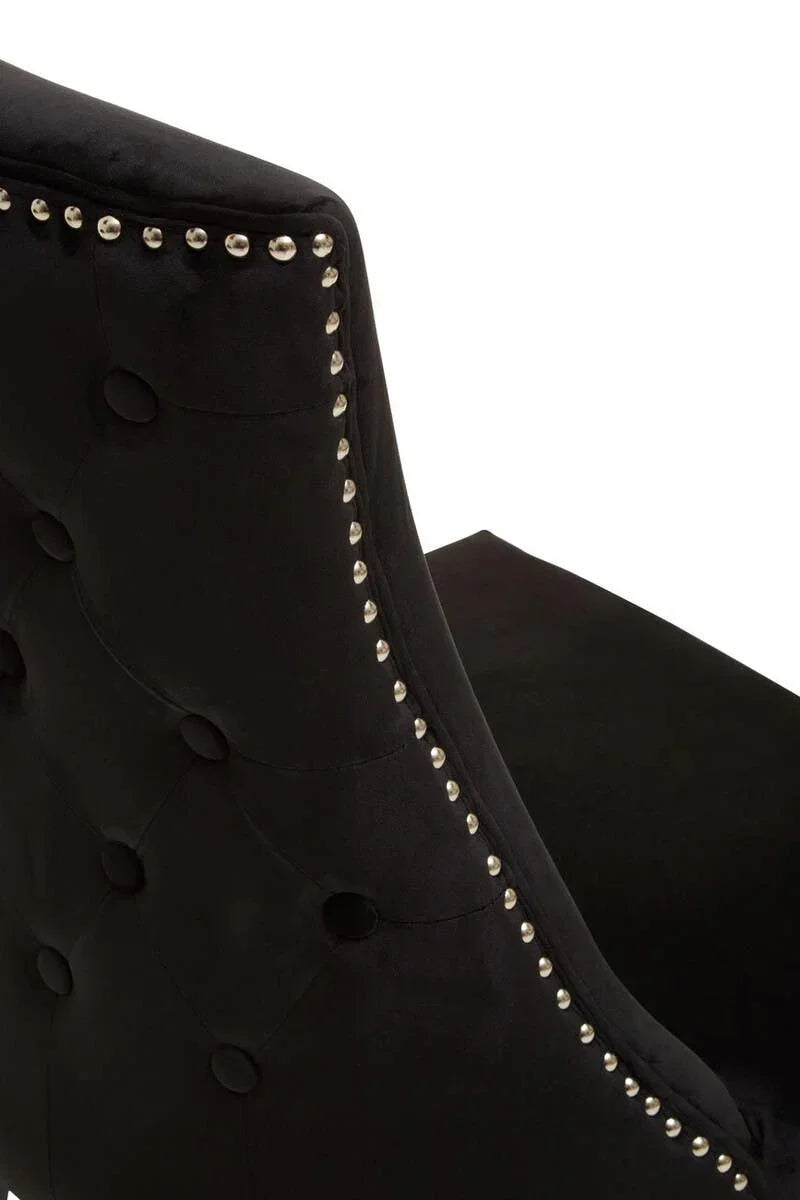 Black velvet dining chair with button tufting and chrome stud trim, rear side view