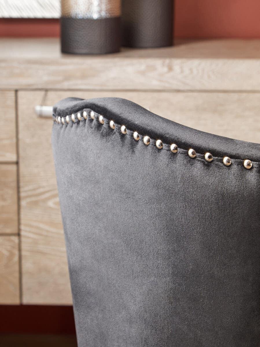 Grey velvet dining chair with silver stud detail in front of wooden desk