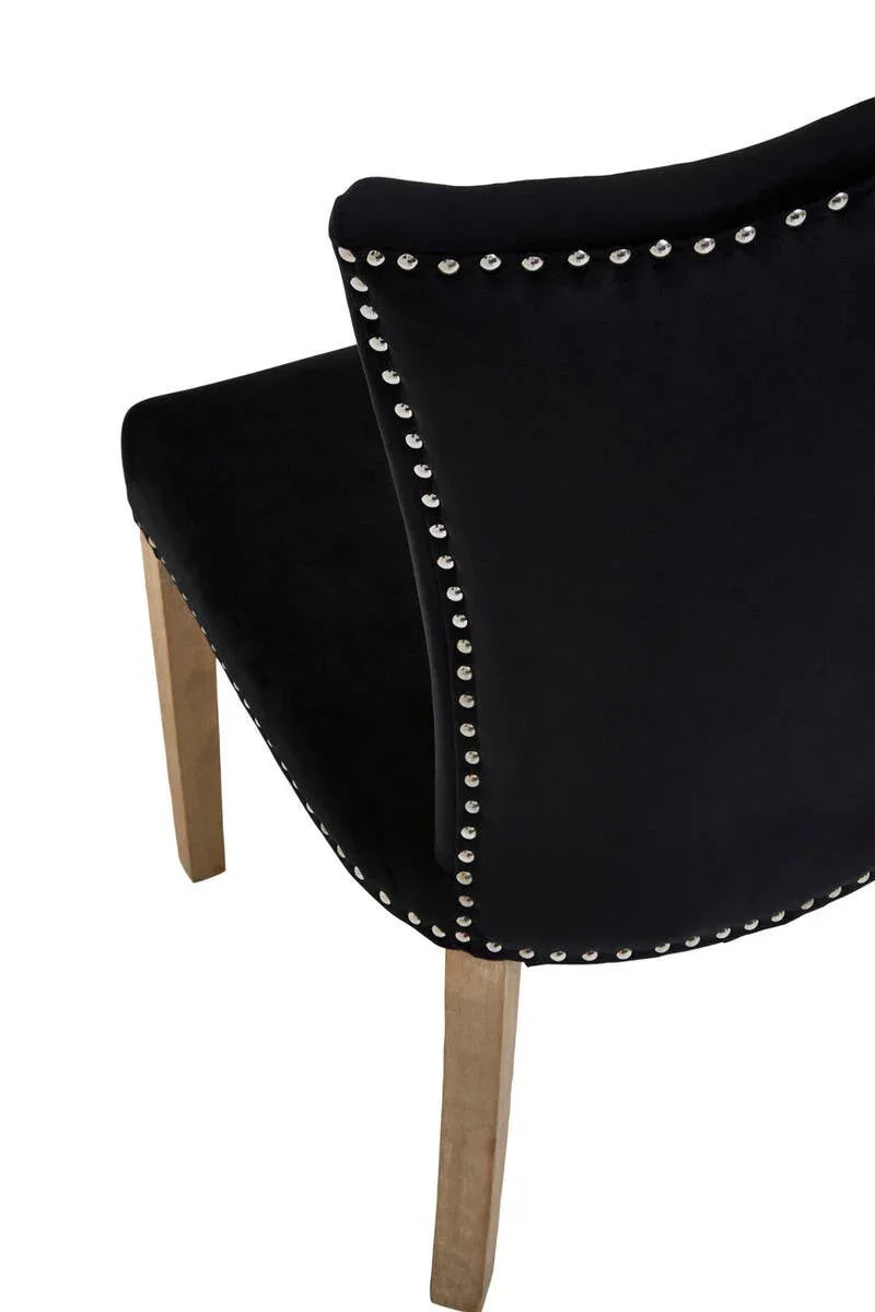 Black velvet dining chair with silver stud detailing and wooden legs, rear angle view