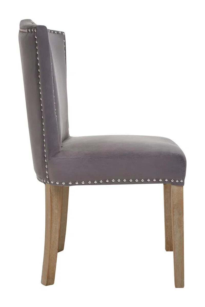 Grey velvet dining chair with wooden legs and silver stud detailing in side profile