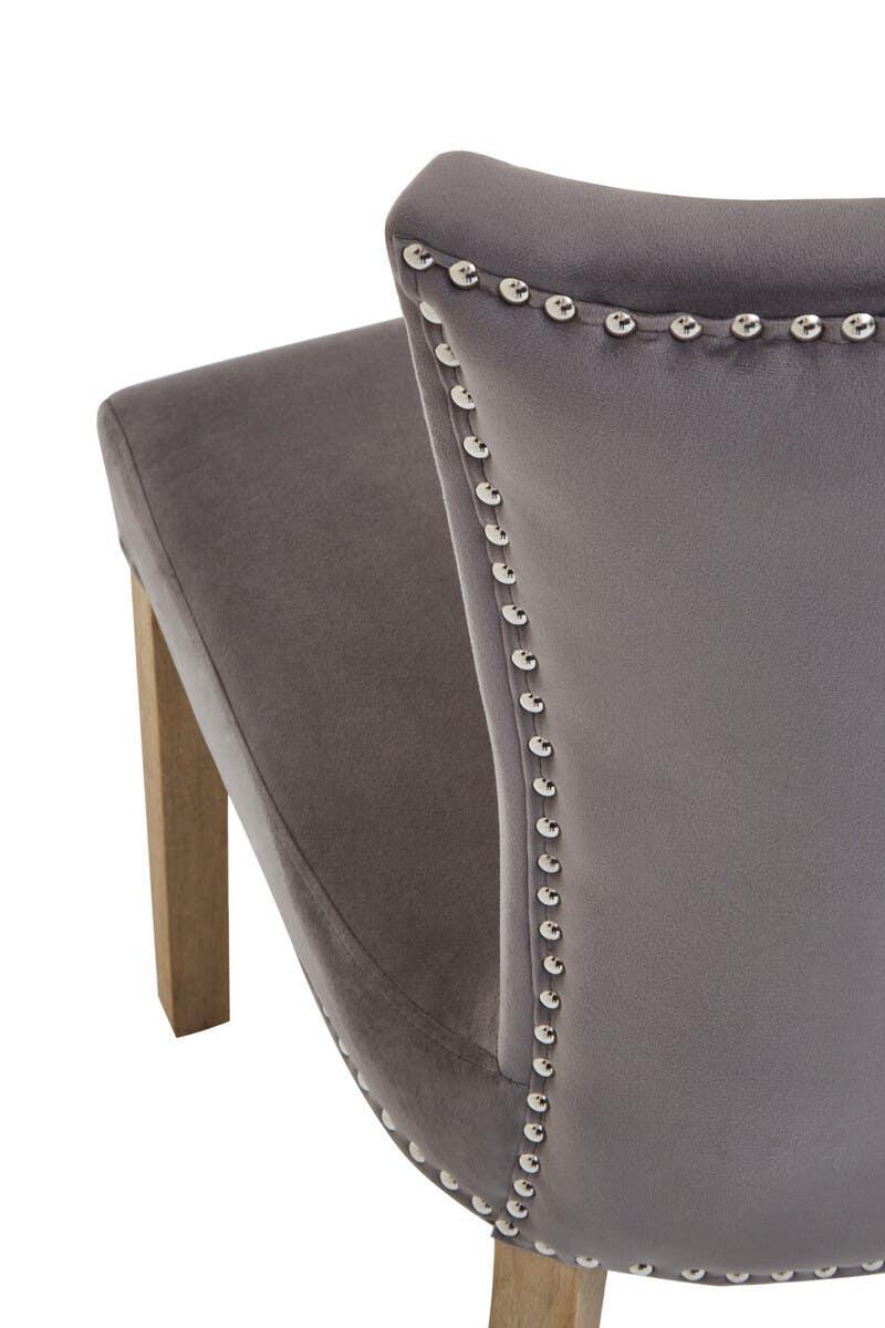 Grey velvet dining chair with silver stud detailing and wooden legs, back angle view