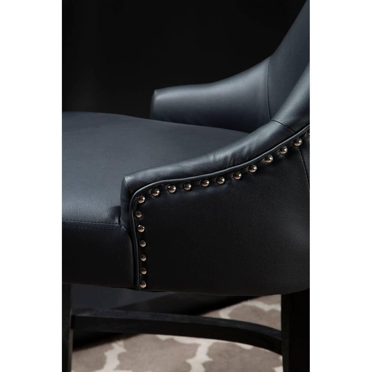 Black leather dining chair with studded trim and armrest detail on patterned rug