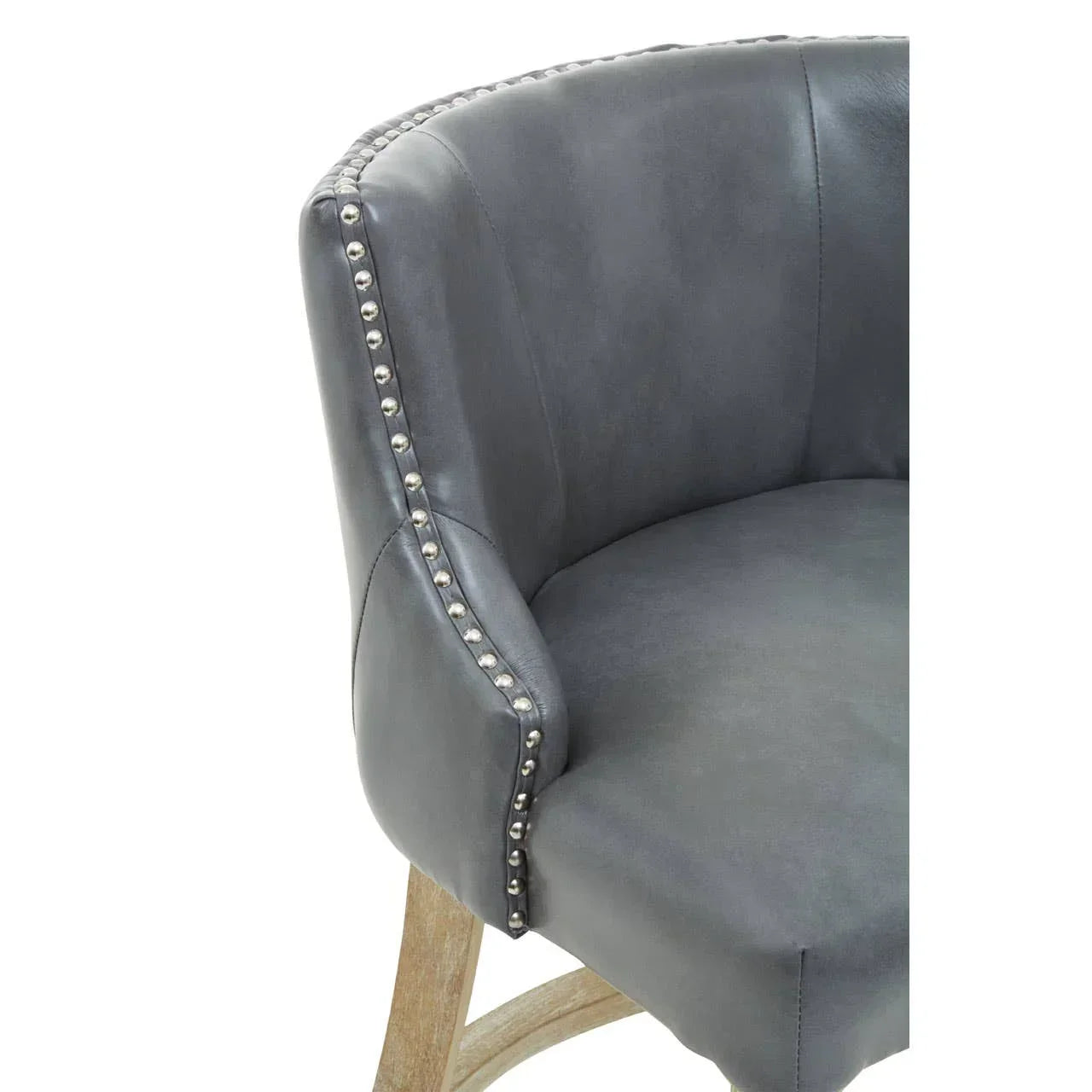 Grey leather accent chair with studded trim and curved wooden legs, close-up view