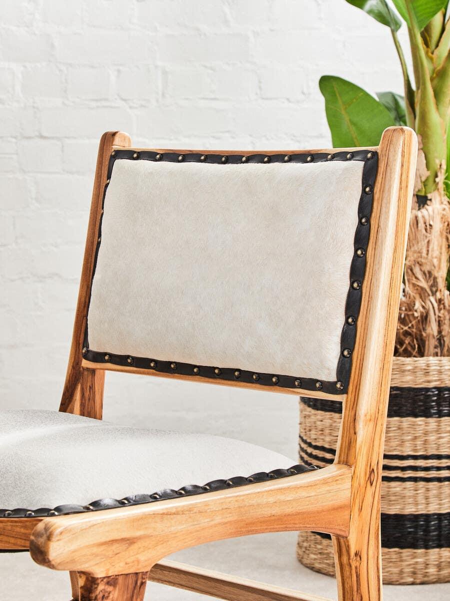 Wooden dining chair with light upholstered seat and backrest, brass studs along edges