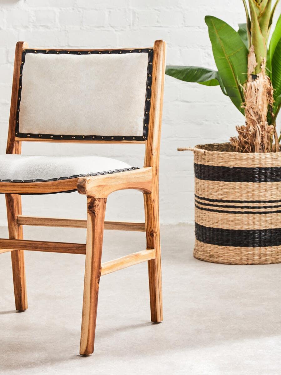 Light wood dining chair with cream upholstered seat and back beside woven plant basket