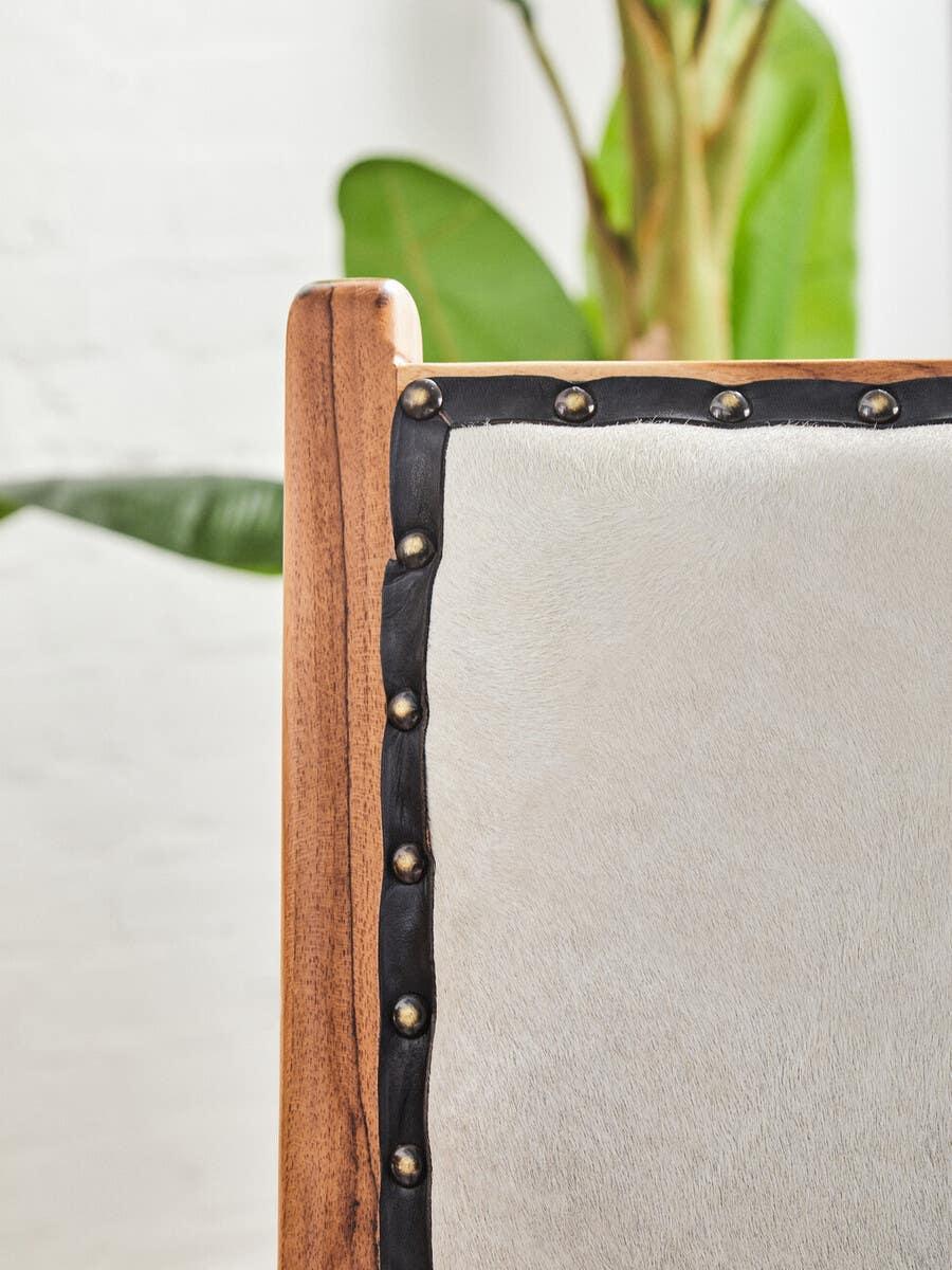 Close-up of dining chair with wooden frame, cream upholstery and stud detailing