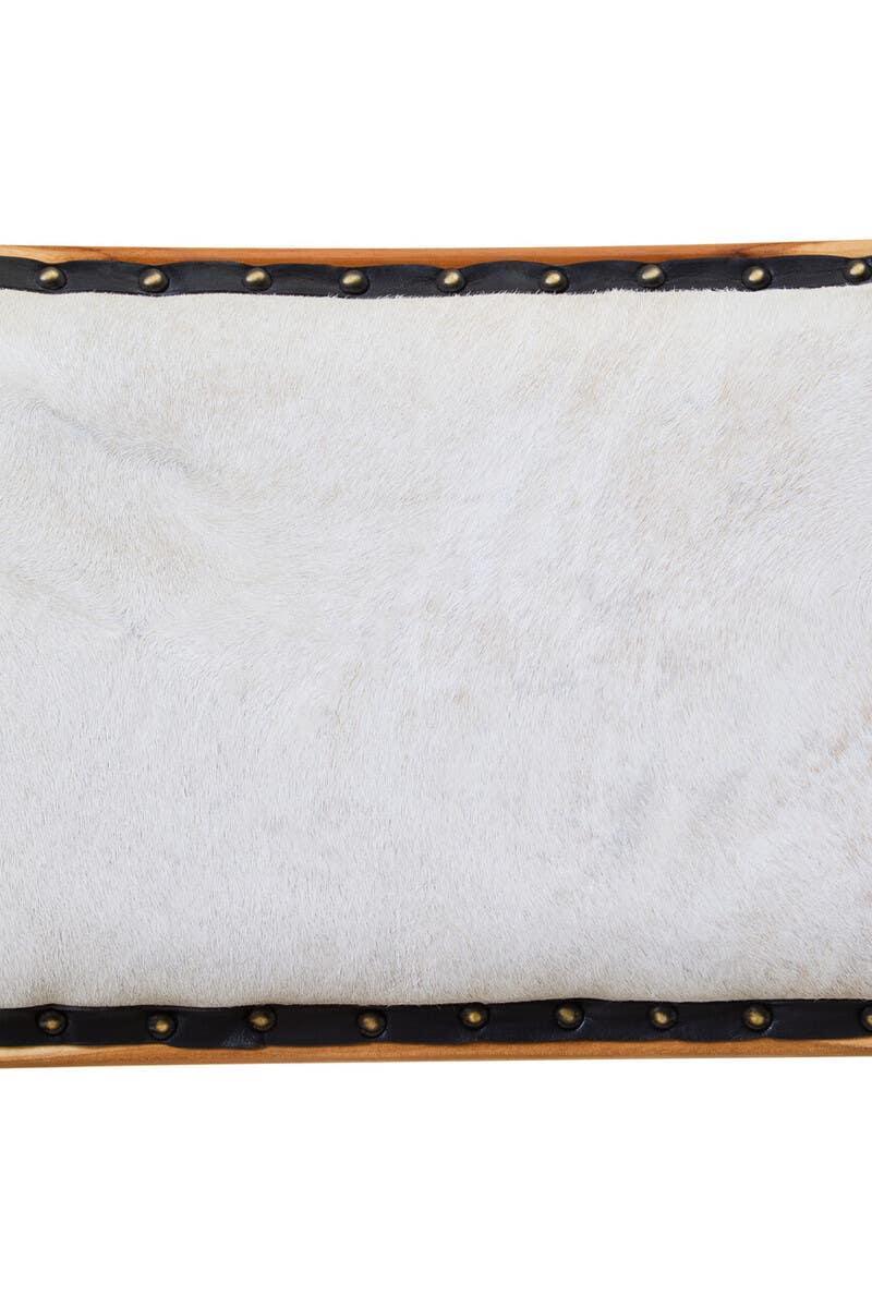 Closeup of white upholstered furniture panel with brass stud detailing and wood trim