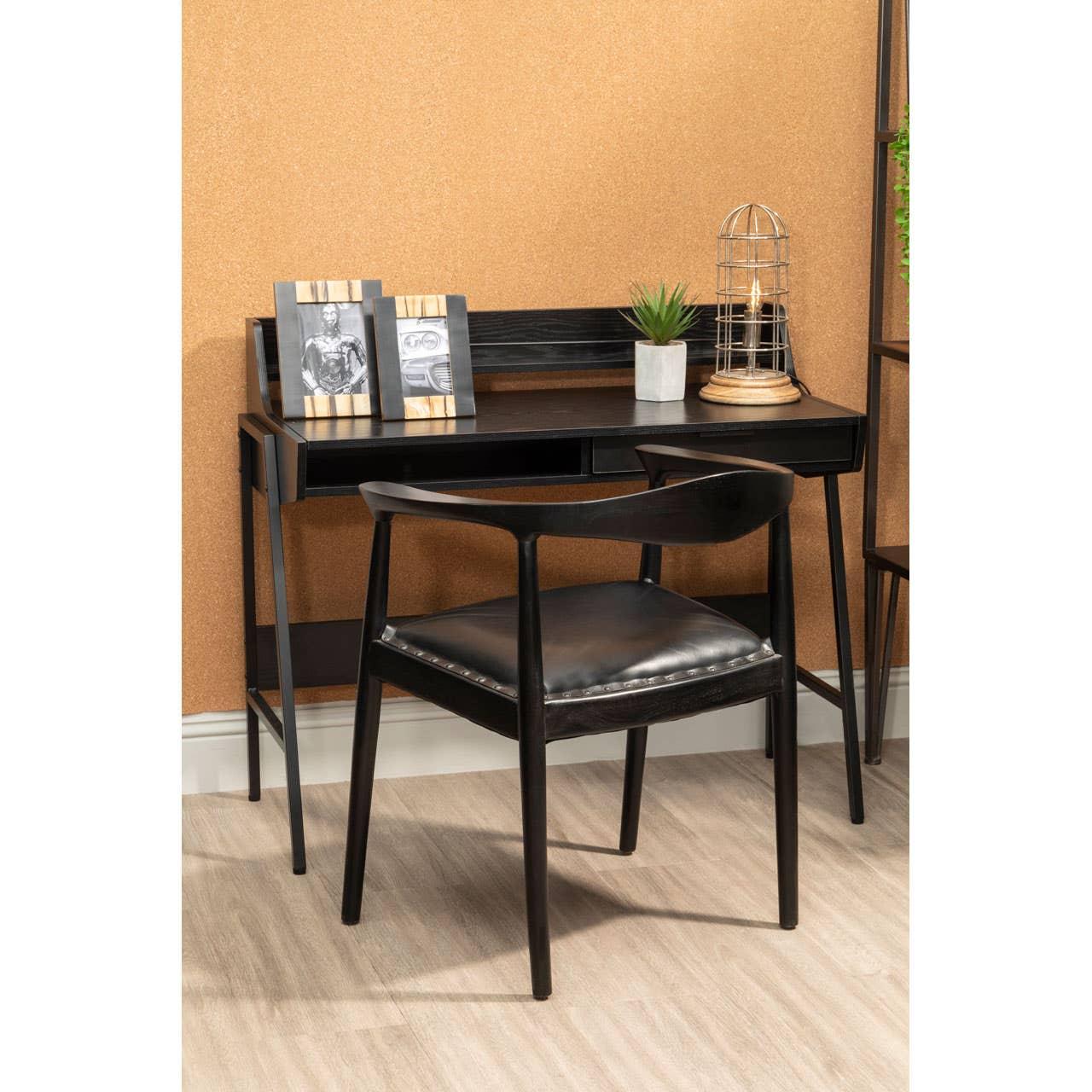 Black wooden desk and matching chair with leather seat, styled with decor in modern home office
