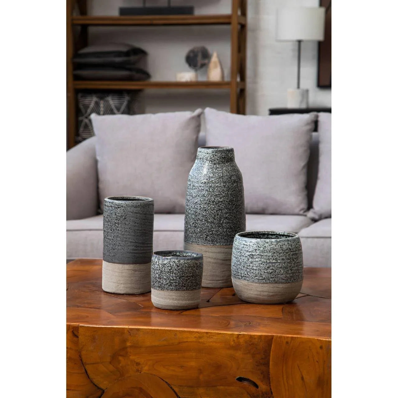 Set of four ceramic vases in grey and beige on wooden coffee table in living room