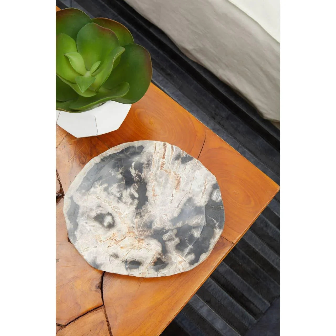 Marble effect decorative plate on wooden side table next to green faux succulent plant