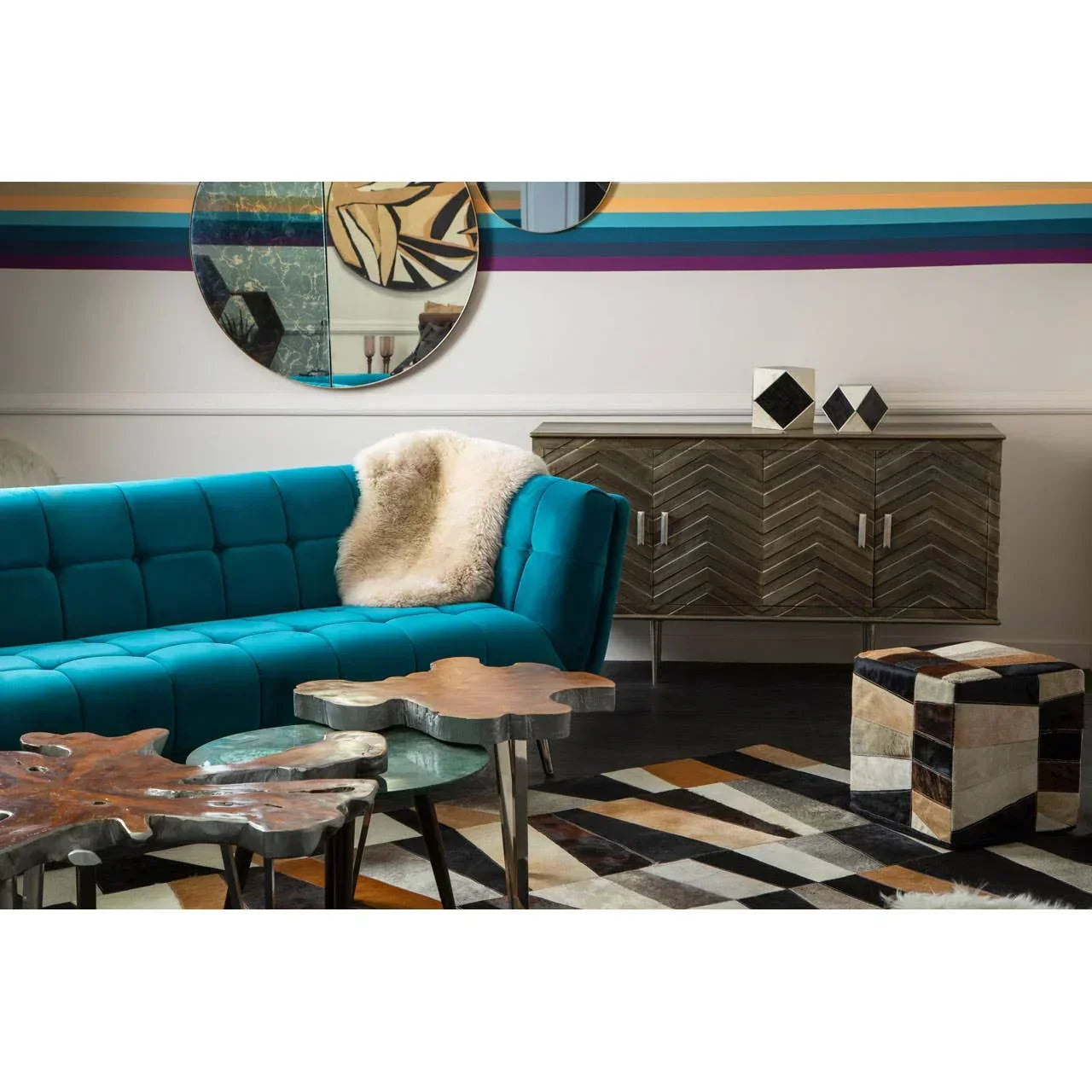 Blue velvet sofa with cream throw, wood side tables, geometric rug, and chevron sideboard