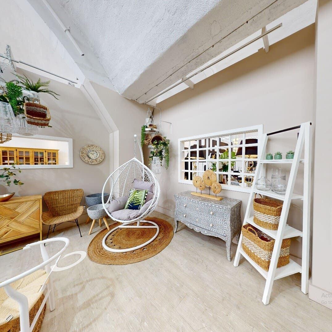 Modern furniture showroom with hanging egg chair, wicker chairs, chest, and display shelves