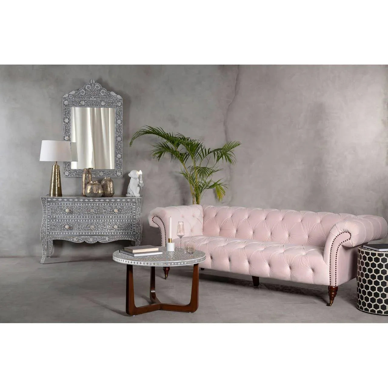 Blush pink tufted sofa with studded arms in modern living room with grey inlay coffee table