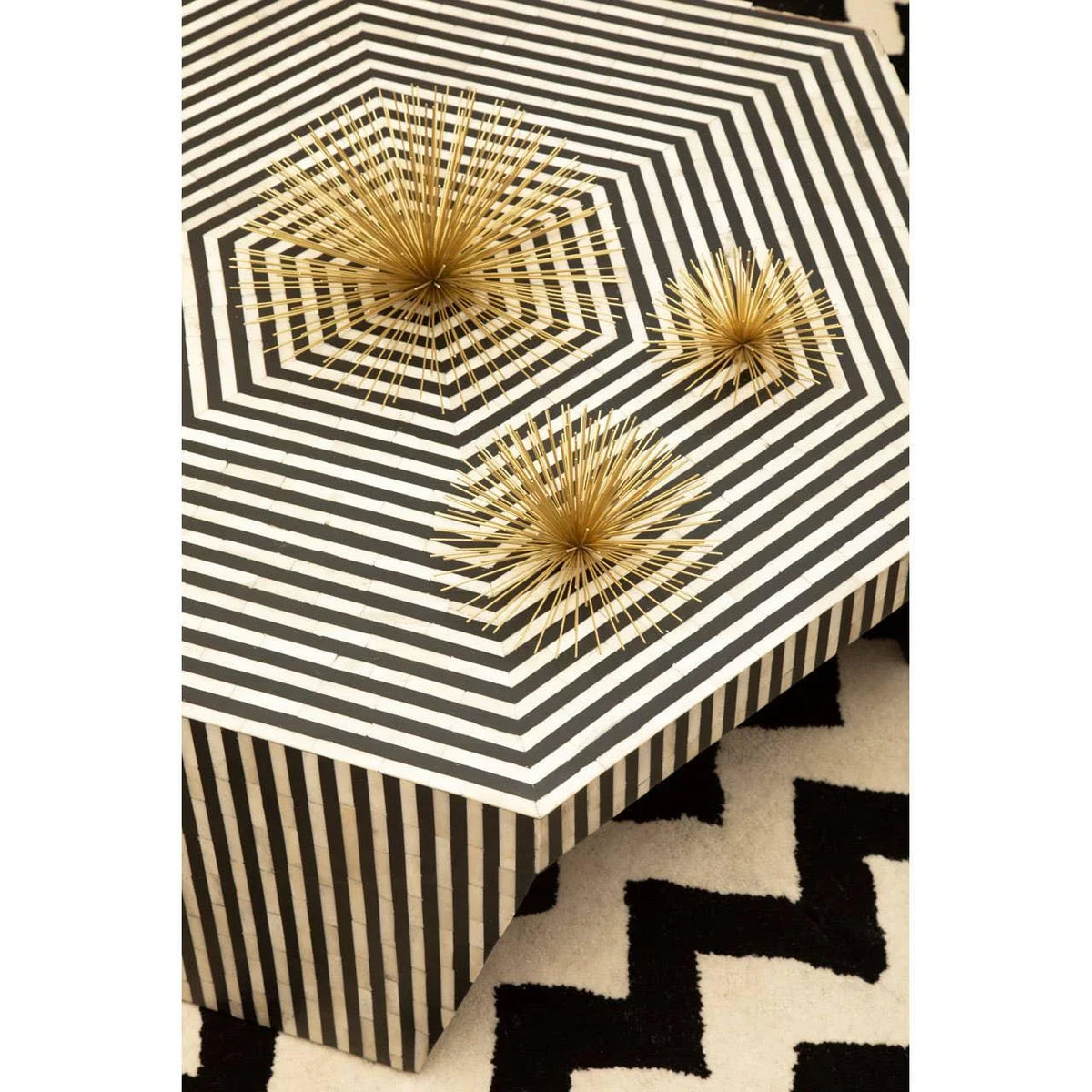 Black and white geometric coffee table with gold spiked decor accents and patterned rug