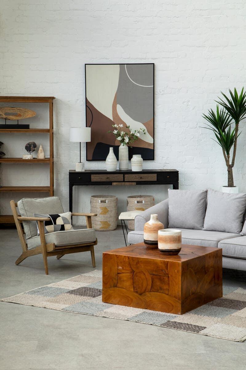 Modern living room with grey sofa, wooden coffee table, armchair and abstract wall art