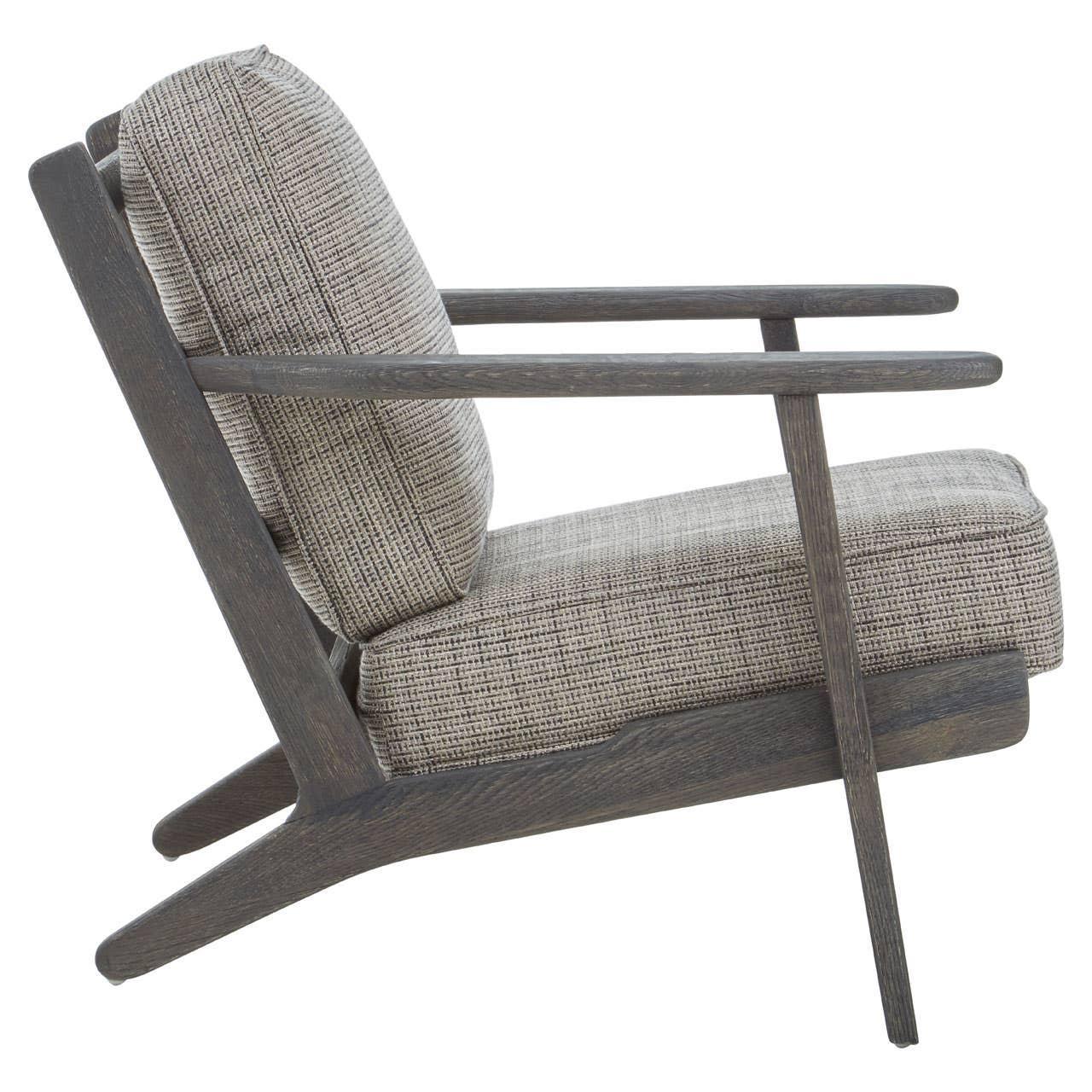 Grey upholstered armchair with wooden frame and angled legs, side profile view